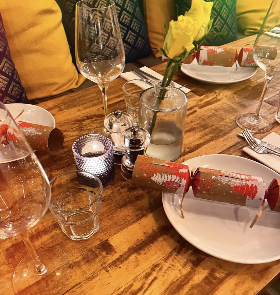 A table at Morleys laid for Christmas, with crackers on the plates, candles and yellow roses