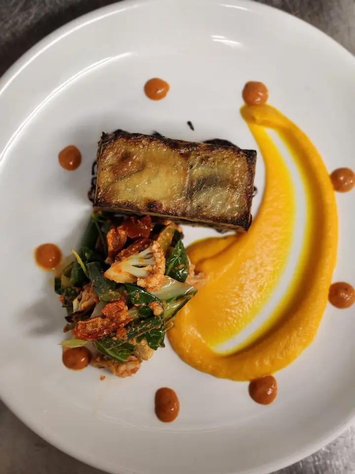 A layered potato terrine with spiced cauliflower, greens and a sweep of squash purée